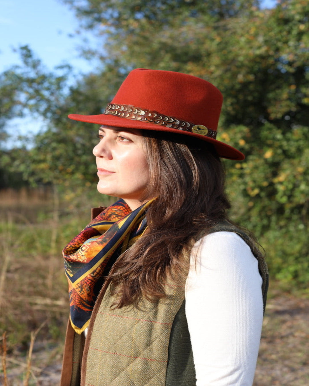 Rust orange felt fedora with pheasant feather wrap, handcrafted by Hayfield England