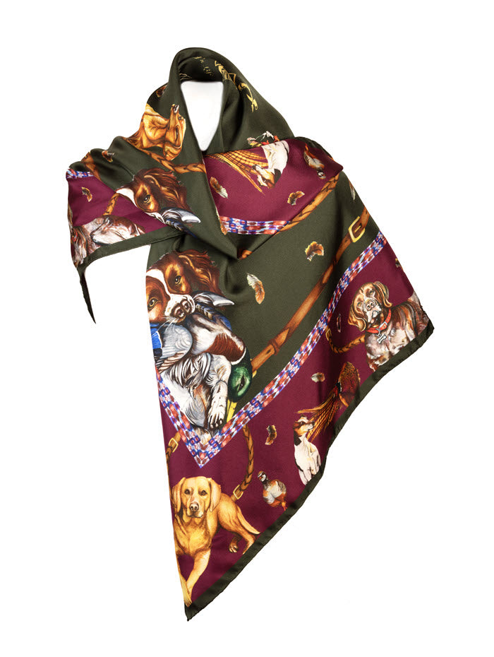 It’s a Dog’s Life large silk scarf featuring detailed illustrations of gun dogs and game birds, in hunter green and oxblood