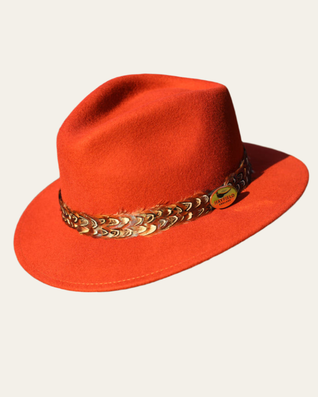 Elegant rust fedora with pheasant feather band, perfect for countryside and city wear